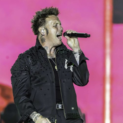 A man with tattoos singing into a microphone.